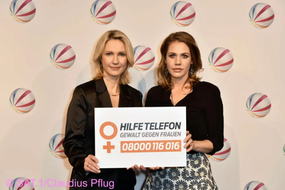 Manuela Schwesig und Schauspielerin Felicitas Woll halten ein Schild in die Höhe