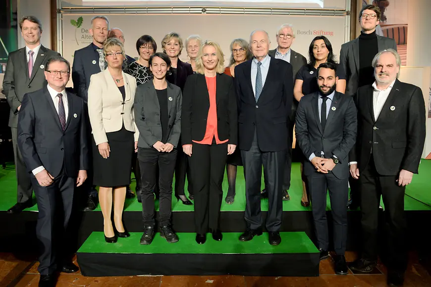 Manuela Schwesig bei der Verleihung des Deutschen Alterspreises mit Nominierten auf einer Bühne