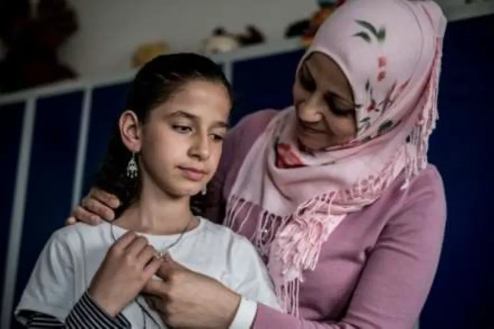 Kopftuch tragende Frau umarmt ihre Tochter