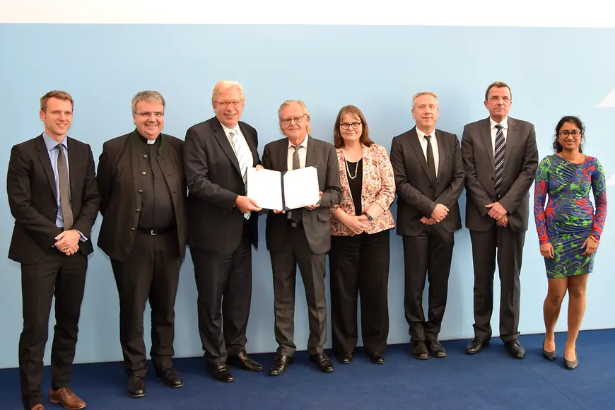 Dr. Ralf Kleindiek mit den Kooperationspartnerinnen und -partnern sowie der unterzeichneten Kooperationsvereinbarung
