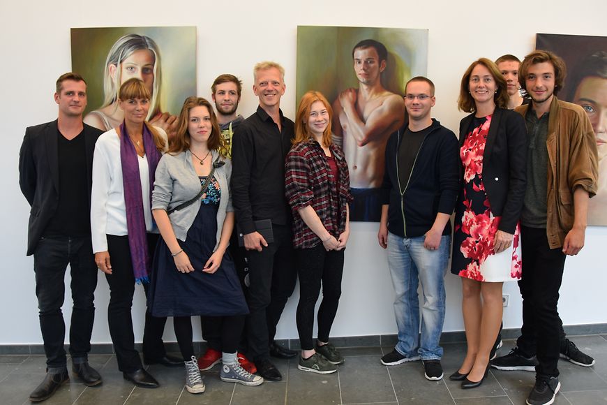 Dr. Katarina Barley mit Jugendlichen, der Künstlerin Babette Brühl und Jörg Richert von KARUNA vor den Bildern im Foyer