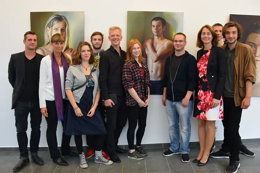 Dr. Katarina Barley mit Jugendlichen, der Künstlerin Babette Brühl und Jörg Richert von KARUNA vor den Bildern im Foyer