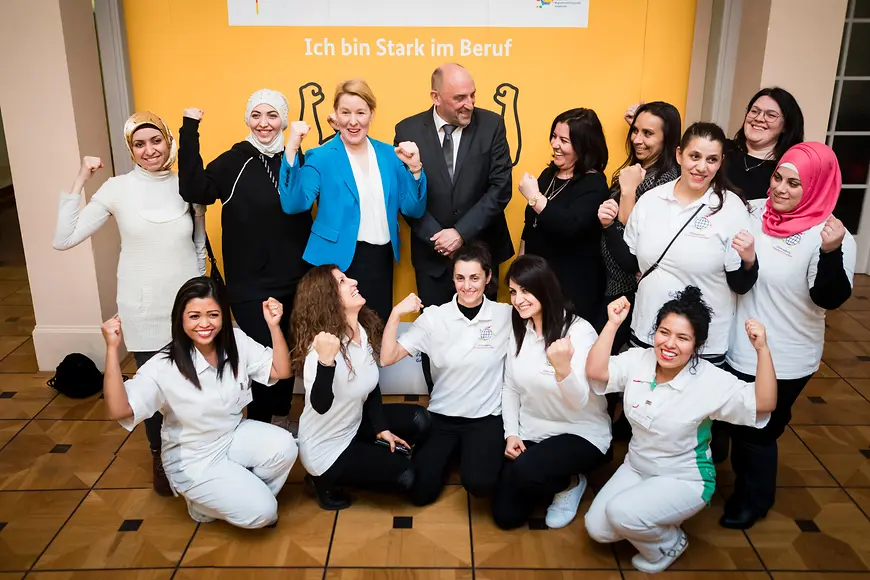 Das Bild zeigt eine Gruppe vor einem Plakat mit dem Slogan Ich bin stark im Beruf