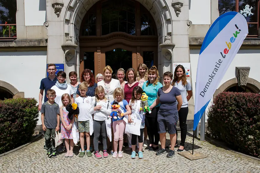 Das Bild zeigt Franziska Giffey in einer Gruppe neben einem Demokratie-Leben-Aufsteller