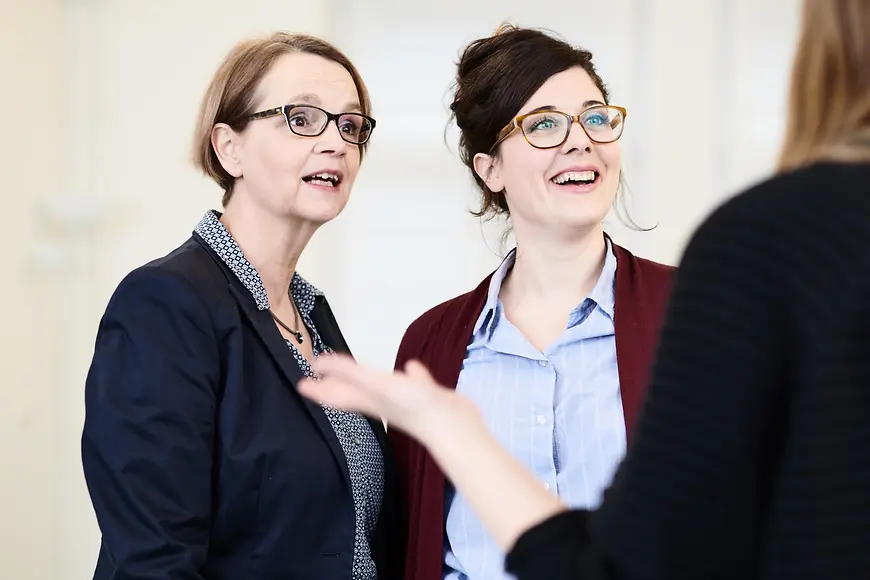 Drei Frauen in Businesskleidung diskutieren.
