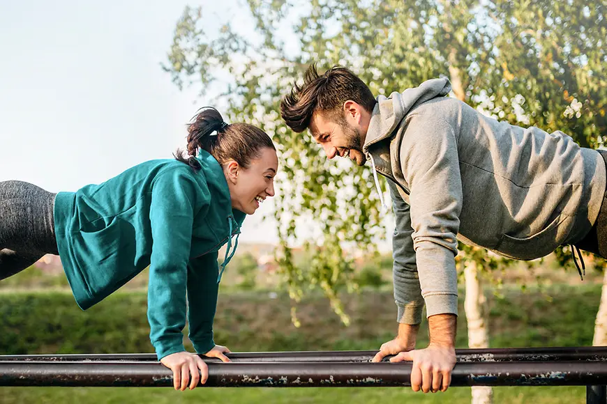 Eine Frau und ein Mann machen Liegestütze im Freien