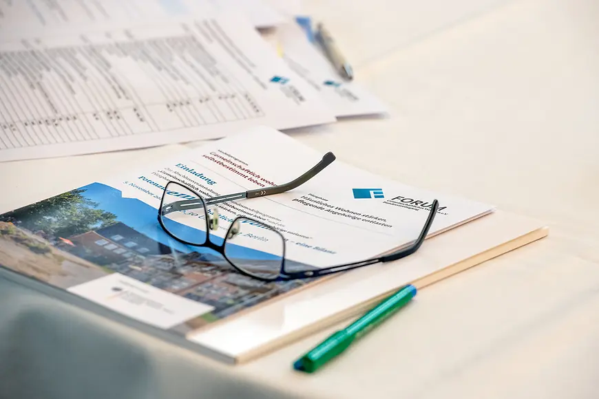 Eine Brille liegt auf der Broschüre des Forum Gemeinschaftliches Wohnen e.V. 