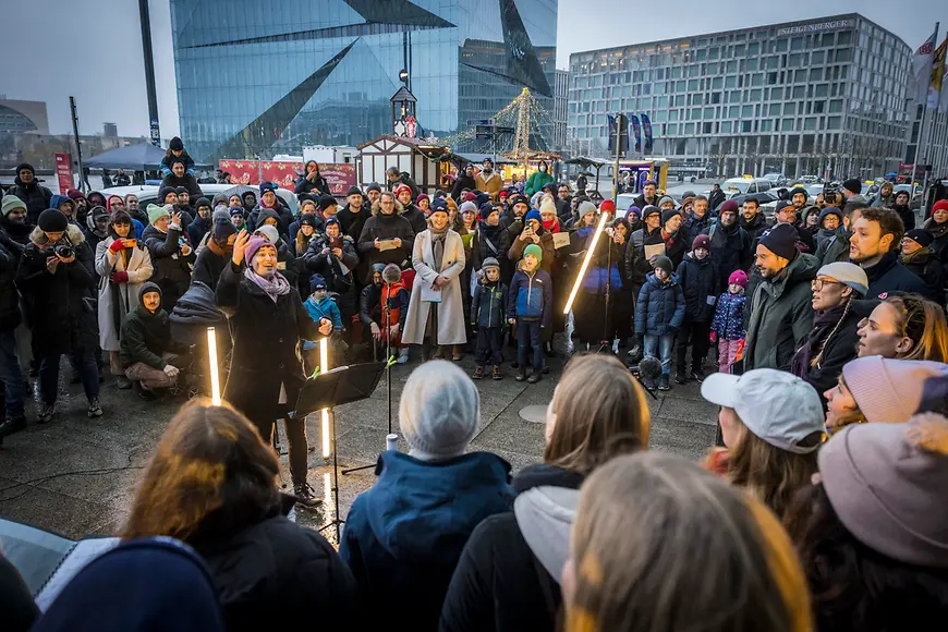 Lisa Paus und eine große Menschengruppe singen gemeinsam am Berliner Hauptbahnhof. 