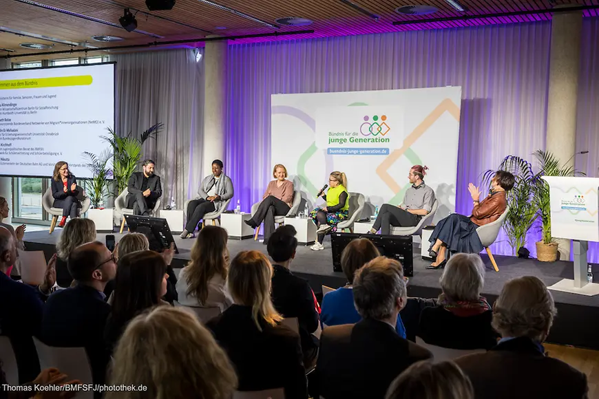 Lisa Paus und weitere Teilnehmende sitzen auf einem Podium