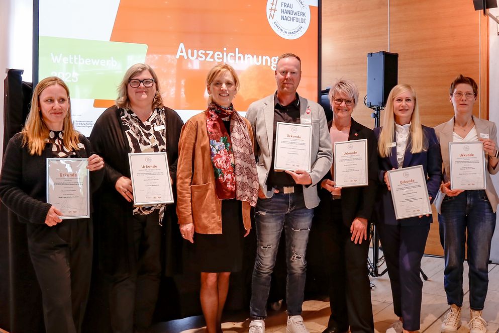Gruppenfoto von Karin Prien und anderen vor Leinwand