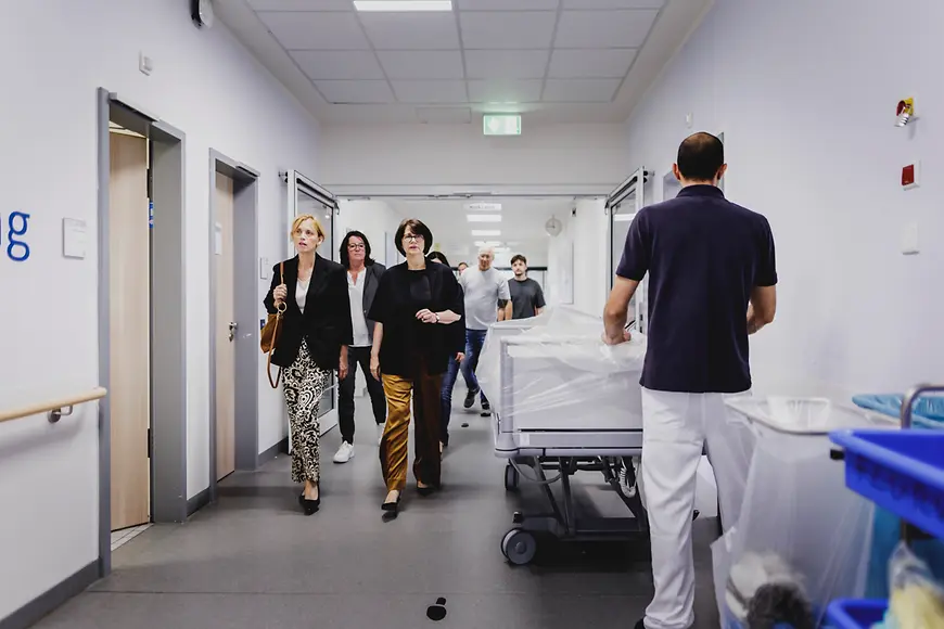 Eine Gruppe von Menschen geht einen Flur in einem Krankenhaus entlang