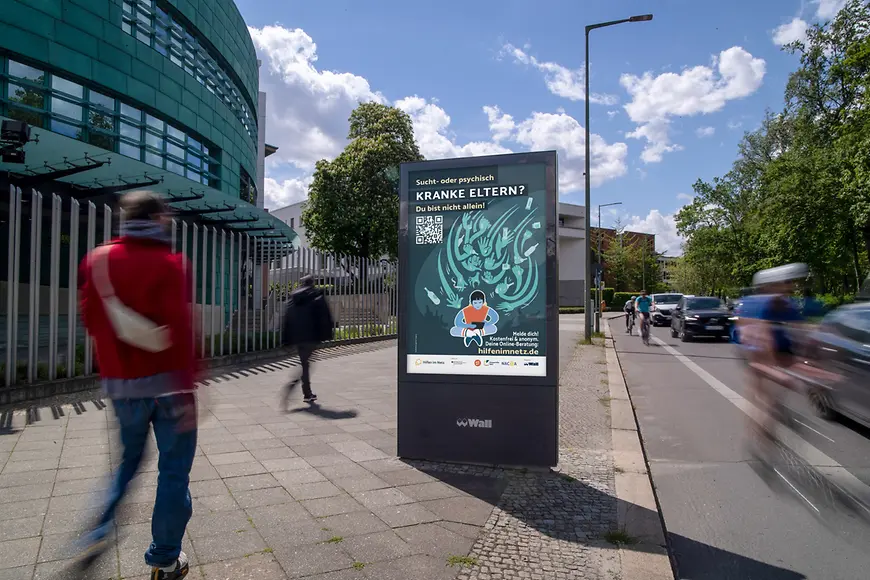  Digitale Werbesäule in einer städtischen Umgebung zeigt ein Plakat der Kampagne für Kinder kranker Eltern