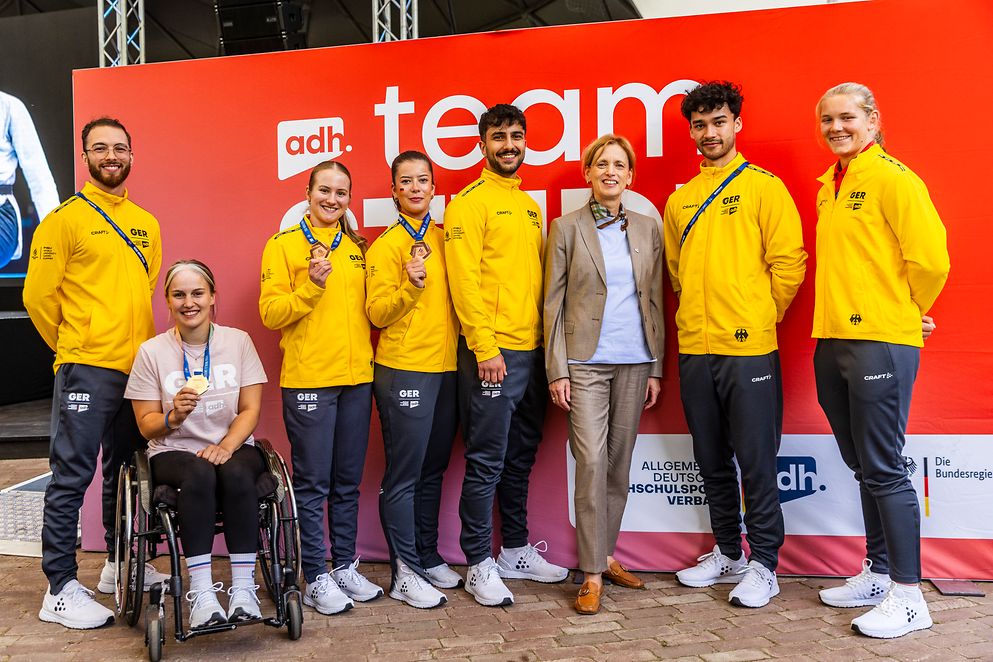 Gruppenbild mit Karin Prien und Jugendlichen vor einem Plakat, eine Frau sitzt im Rollstuhl