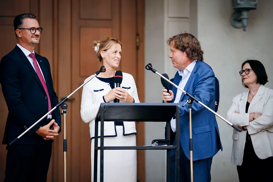 Karin Prien steht mit weiteren Personen an einem Rednerpult 