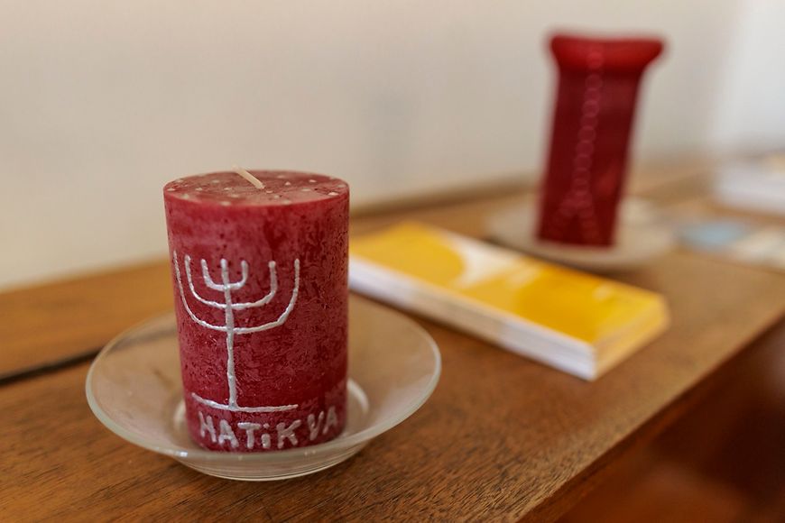 Eine rote Kerze, auf der ein siebenarmiger Leuchter und die Aufschrift "HATiKVA" abgebildet ist