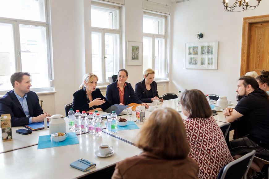 Mehrere Menschen sitzen an einem großen Tisch und unterhalten sich