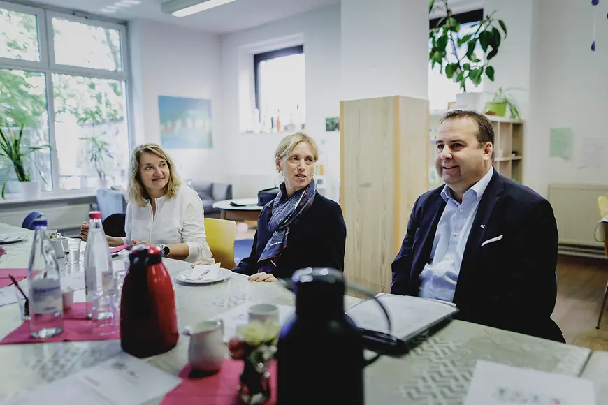 Karin Prien und Dr. Magnus Jung sitzen an einem Tisch und unterhalten sich