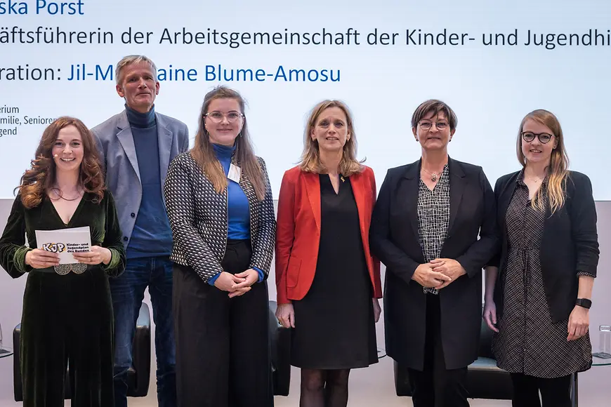Karin Prien und andere auf Podium vor Leinwand