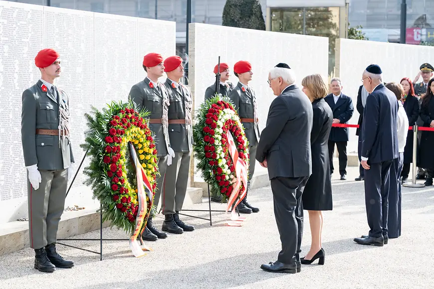Frank-Walter Steinmeier und Elke Büdenbender stehen mit geneigtem Kopf vor zwei Gedenkkränzen