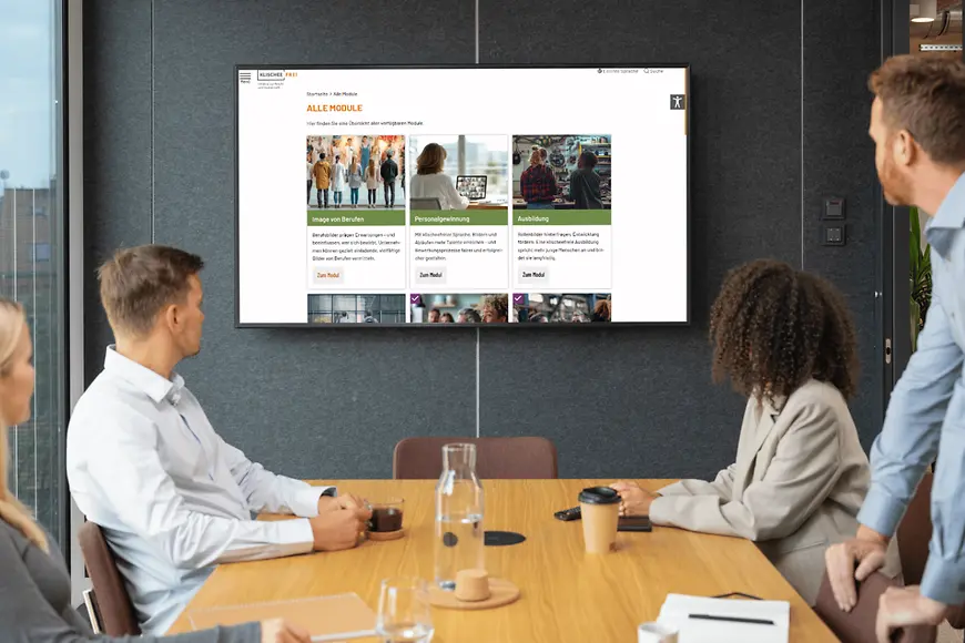 Eine Gruppe Personen blickt auf einen Bildschirm