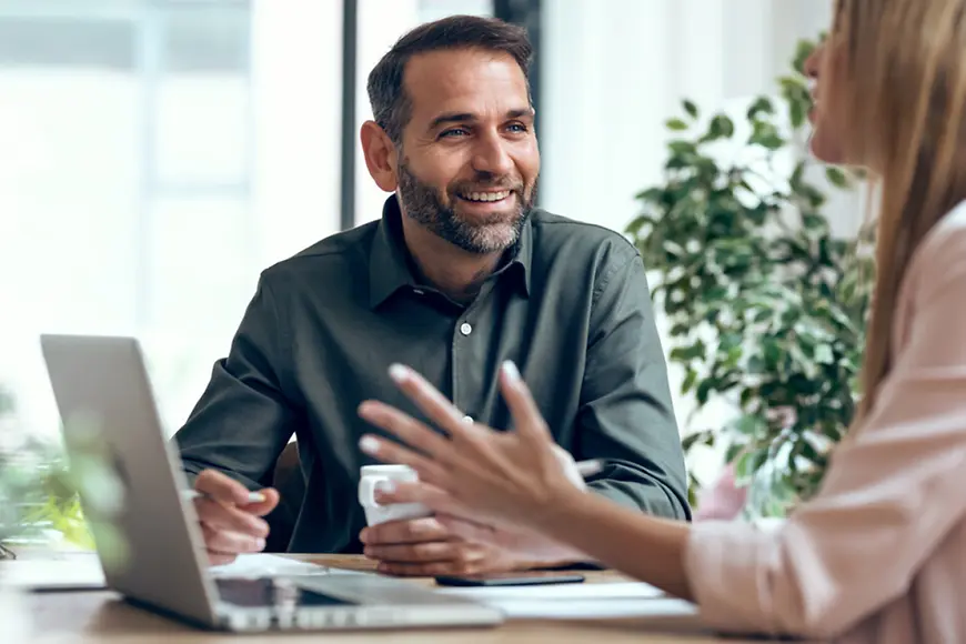 Ein Mann und eine Frau an einem Schreibtisch in einer Beratungssituation
