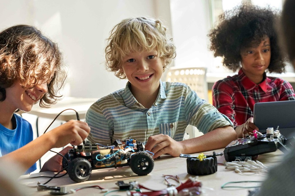 Lachende Kinder spielen mit technischen Geräten