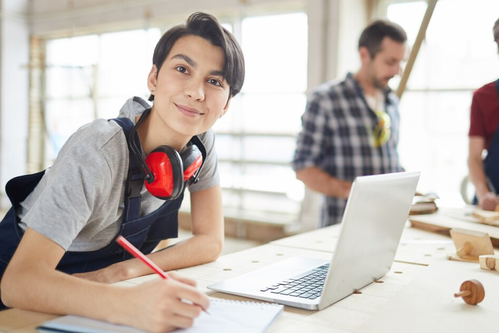 Tischlerin, die am Laptop in der Tischlerei arbeitet