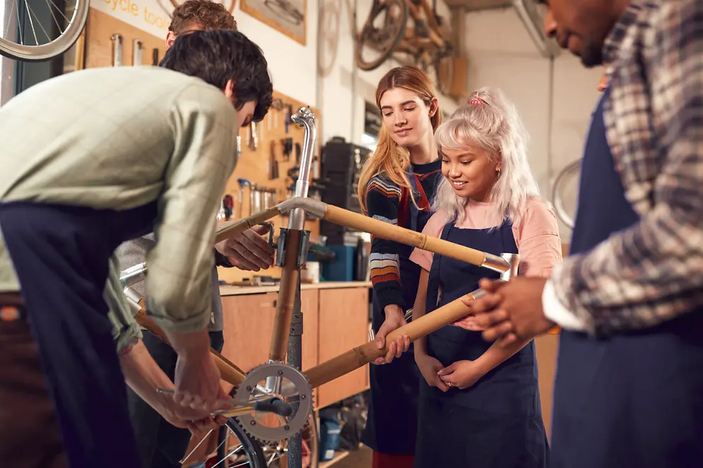 Auszubildende arbeiten gemeinsam in einer Werkstatt an einem Fahrrad aus Bambus.