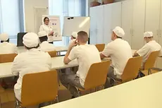 Bäckerauszubildende sitzen in einer Klasse an Tischen