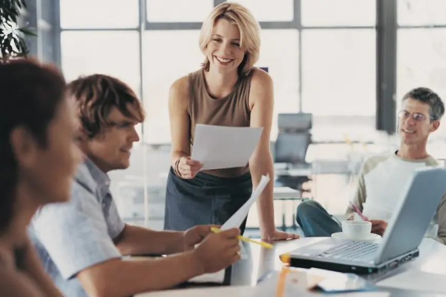 Frauen und Männer sitzen am Tisch und arbeiten. 
