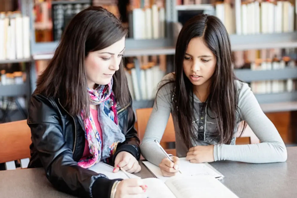 Erwachsene hilft Mädchen bei den Hausaufgaben