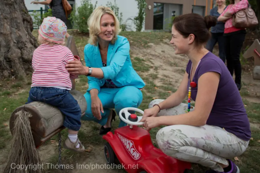 Manuela Schwesig im Gespräch mit einer Mutter. Daneben spielt ein Kleinkind.